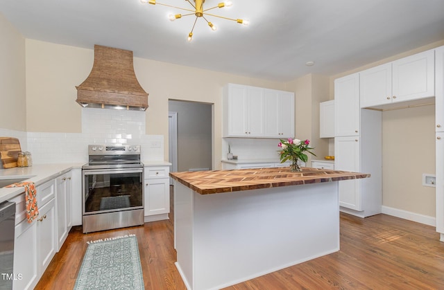 kitchen featuring stainless steel range with electric stovetop, butcher block counters, custom exhaust hood, and wood finished floors