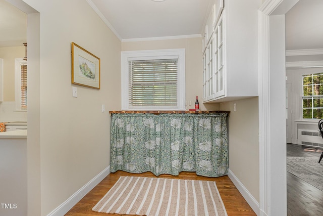 bar with baseboards, crown molding, radiator heating unit, and wood finished floors