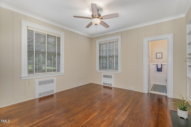 empty room featuring ornamental molding, a decorative wall, wood finished floors, and radiator