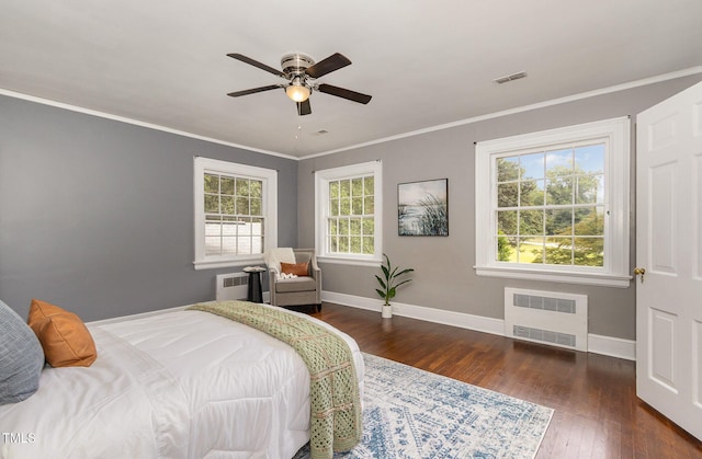 bedroom with crown molding, visible vents, hardwood / wood-style floors, radiator heating unit, and baseboards