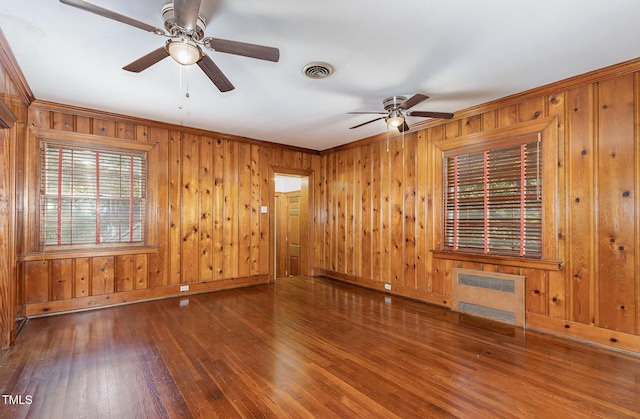 unfurnished room with heating unit, visible vents, ceiling fan, baseboards, and hardwood / wood-style flooring