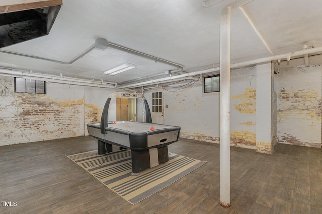 game room with brick wall and wood finished floors