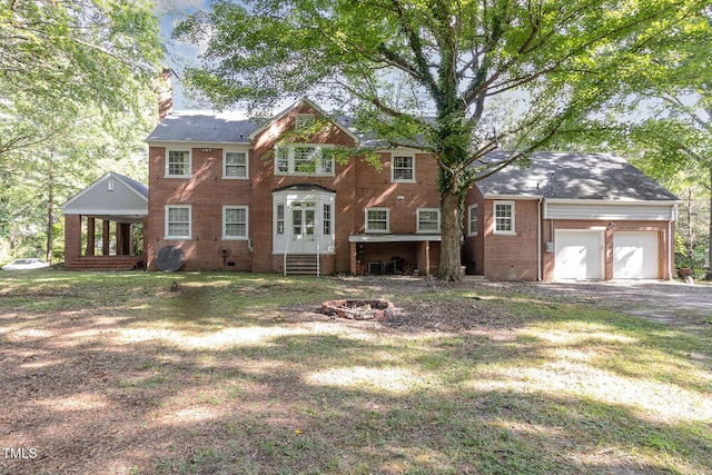 view of front facade with a garage, driveway, a fire pit, crawl space, and brick siding