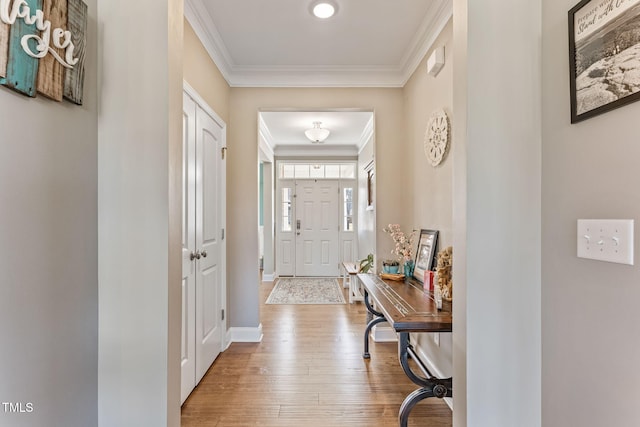 foyer featuring baseboards, wood finished floors, and crown molding