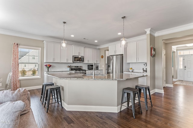 kitchen with a sink, appliances with stainless steel finishes, an island with sink, a kitchen bar, and crown molding