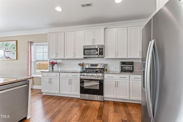 kitchen with visible vents, white cabinets, appliances with stainless steel finishes, tasteful backsplash, and dark wood finished floors