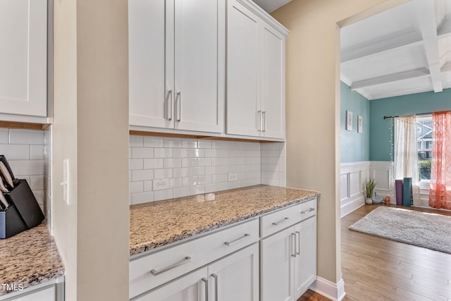 kitchen featuring coffered ceiling, wood finished floors, white cabinetry, and light stone countertops