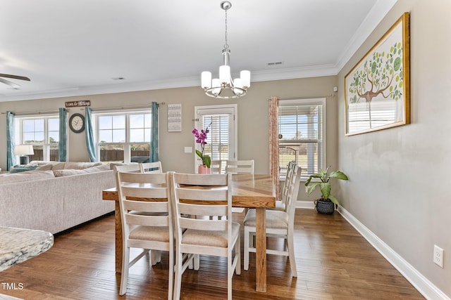 dining space featuring ceiling fan with notable chandelier, visible vents, baseboards, dark wood finished floors, and crown molding