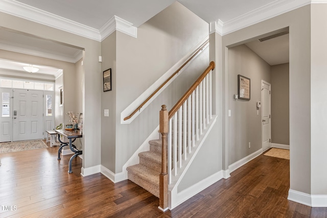 stairway featuring baseboards, wood finished floors, visible vents, and crown molding