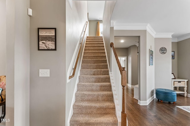 staircase featuring ornamental molding, baseboards, and wood finished floors