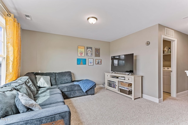 living room with washer / dryer, visible vents, carpet floors, and baseboards