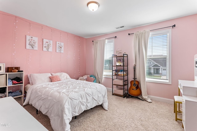 carpeted bedroom featuring visible vents, baseboards, and multiple windows