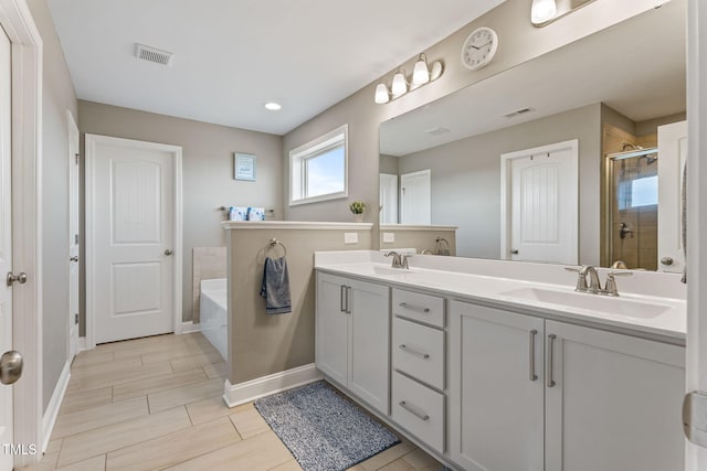 bathroom with a stall shower, visible vents, a sink, and a garden tub