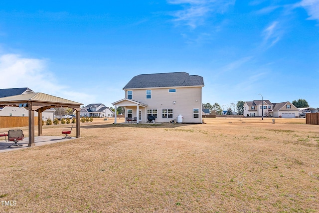 rear view of property featuring fence, a lawn, a patio, and a gazebo