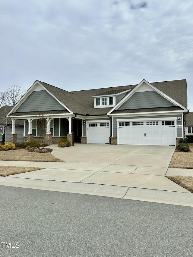 view of front of house featuring a garage, driveway, roof with shingles, a porch, and brick siding