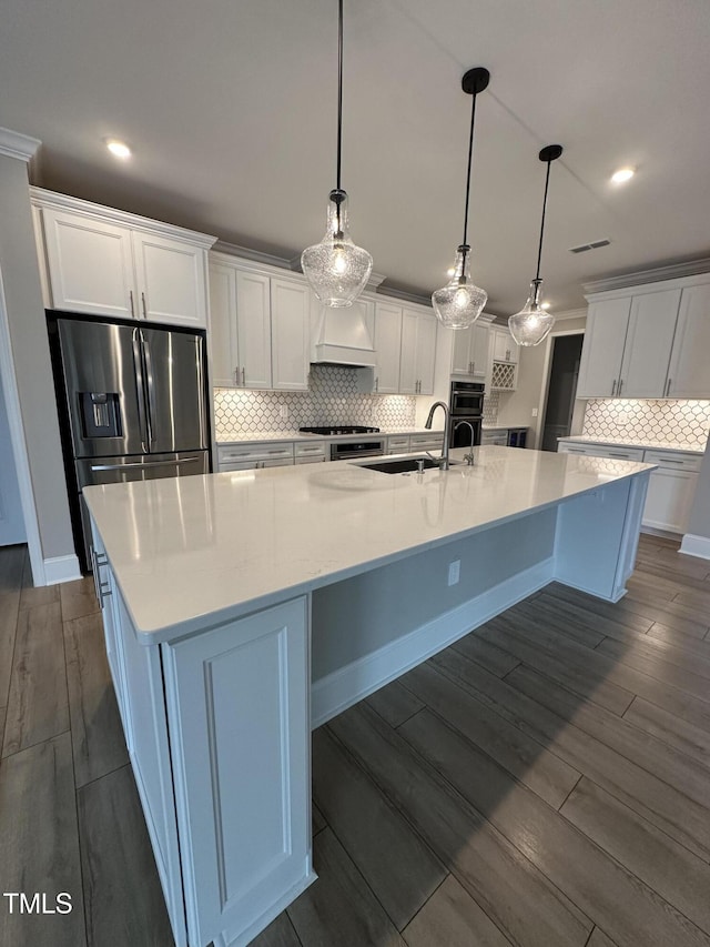 kitchen with white cabinets, dark wood finished floors, premium range hood, stainless steel refrigerator with ice dispenser, and a sink