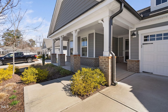 property entrance featuring a garage, brick siding, and covered porch