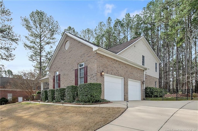 view of home's exterior with a garage, concrete driveway, fence, a yard, and brick siding