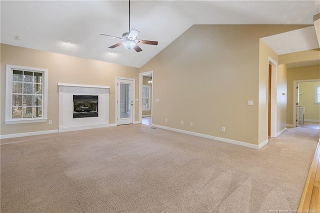 unfurnished living room with baseboards, light colored carpet, a tile fireplace, ceiling fan, and high vaulted ceiling