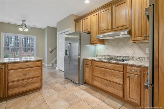 kitchen with freestanding refrigerator, light tile patterned flooring, stainless steel fridge, under cabinet range hood, and black electric cooktop