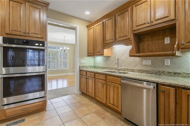 kitchen featuring light tile patterned floors, light stone counters, stainless steel appliances, a sink, and tasteful backsplash