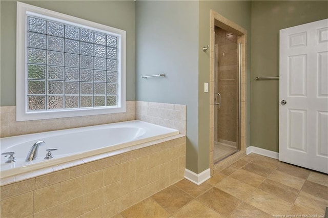 bathroom featuring a garden tub, a shower stall, and baseboards