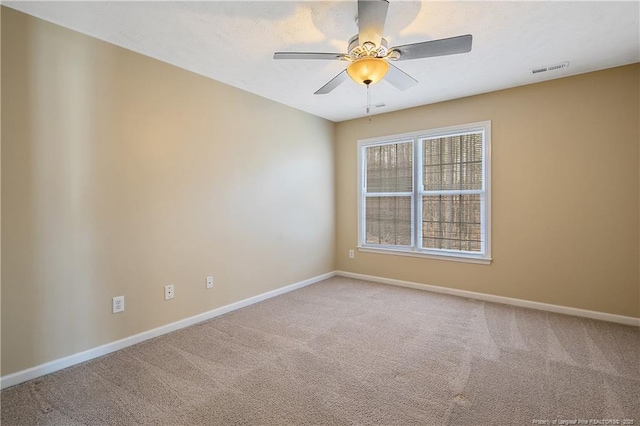 empty room with ceiling fan, carpet floors, visible vents, and baseboards