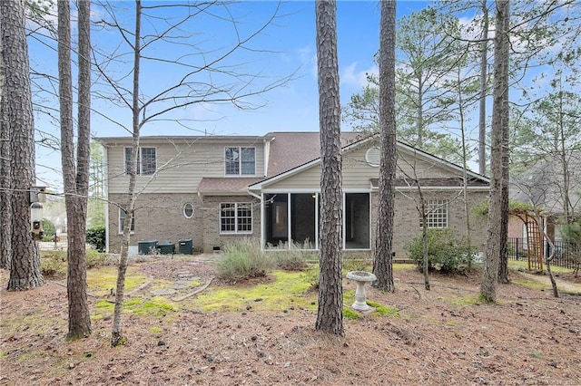 back of house featuring a sunroom, brick siding, and fence