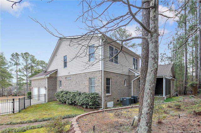 view of side of home with a garage, central AC unit, a sunroom, fence, and brick siding