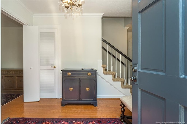 entrance foyer featuring wood finished floors, stairs, and ornamental molding