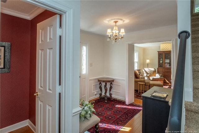 interior space featuring wood finished floors, a notable chandelier, ornamental molding, and a decorative wall