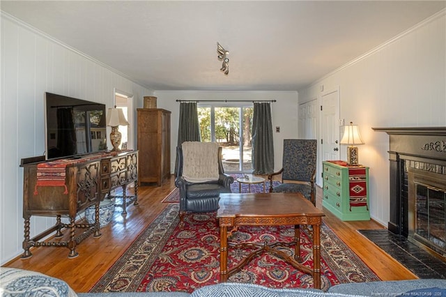 living area with a brick fireplace, crown molding, and wood finished floors