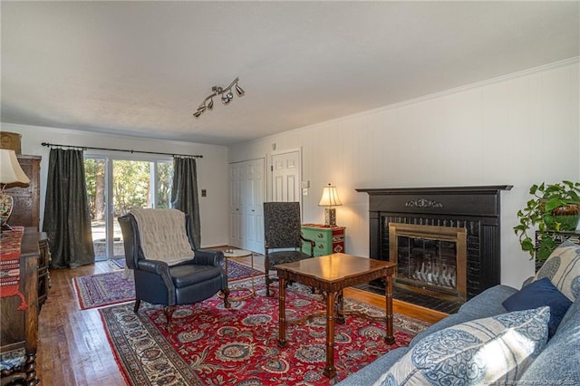 living area with a fireplace, wood-type flooring, and ornamental molding