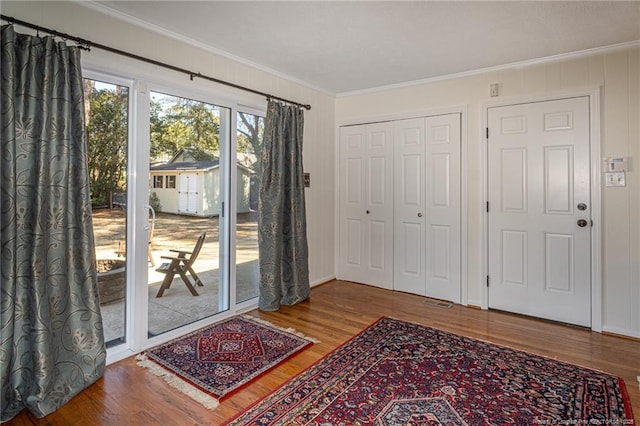 entryway with wood finished floors and ornamental molding