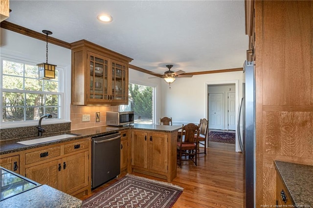 kitchen with a sink, appliances with stainless steel finishes, a peninsula, and brown cabinetry