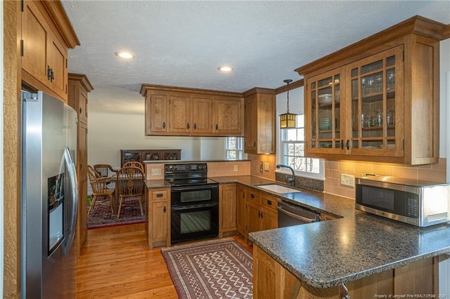 kitchen featuring a sink, stainless steel appliances, dark countertops, and a peninsula