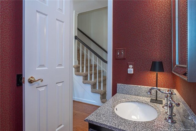 bathroom with wallpapered walls, vanity, and wood finished floors