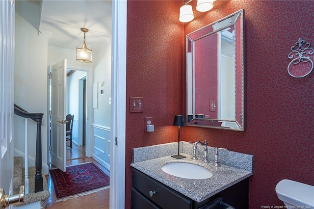 bathroom featuring wood finished floors, toilet, ornamental molding, and vanity