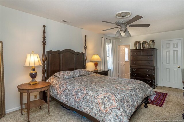 bedroom featuring visible vents, light colored carpet, baseboards, and ceiling fan