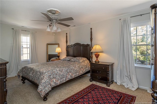 bedroom featuring multiple windows, a ceiling fan, visible vents, and light carpet