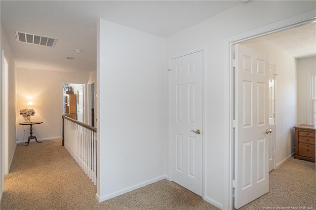 hall with light colored carpet, visible vents, and baseboards