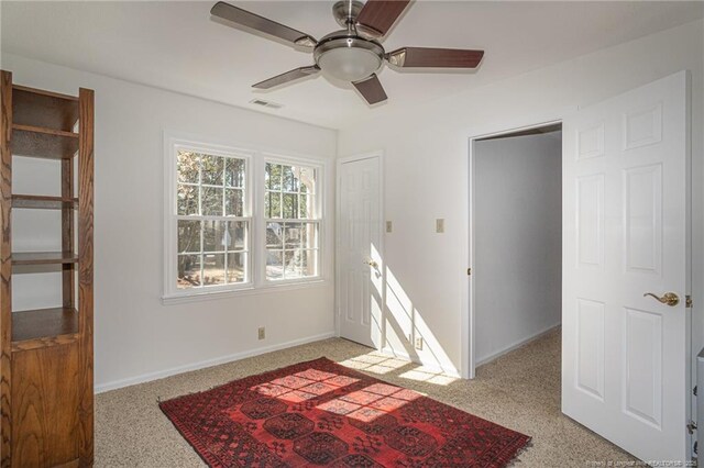 empty room featuring visible vents, light colored carpet, baseboards, and ceiling fan