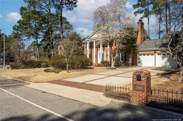 neoclassical / greek revival house with fence, an attached garage, a chimney, decorative driveway, and brick siding