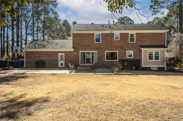 rear view of property with a patio, brick siding, and a chimney