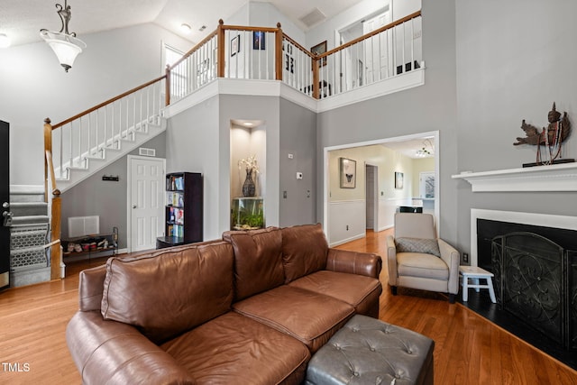 living area featuring stairway, a fireplace, visible vents, and wood finished floors