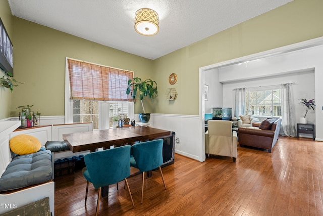 dining room featuring a textured ceiling, wainscoting, and wood-type flooring