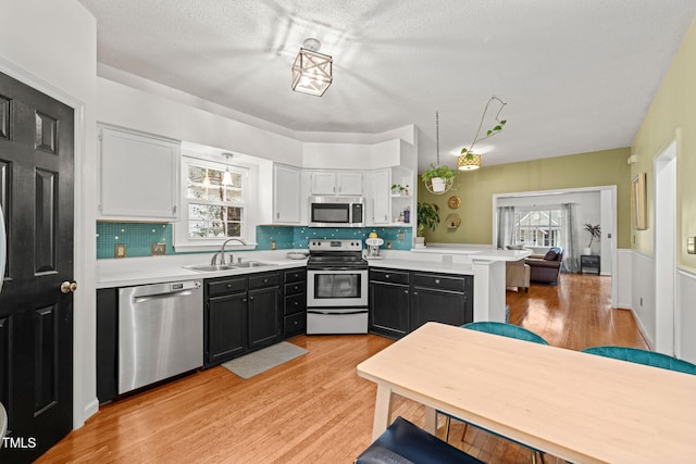 kitchen with light wood-type flooring, appliances with stainless steel finishes, light countertops, and a sink