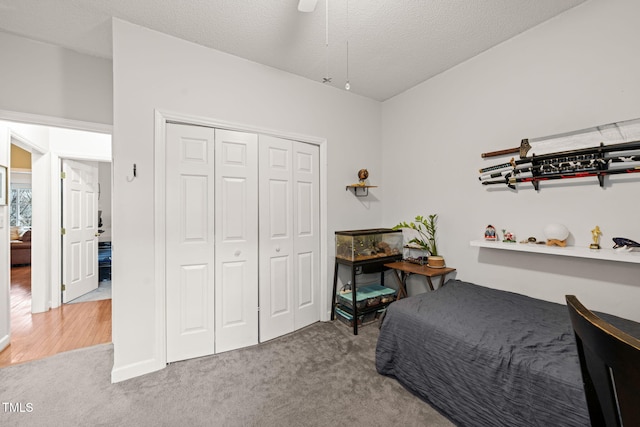 carpeted bedroom with a textured ceiling, ceiling fan, and a closet