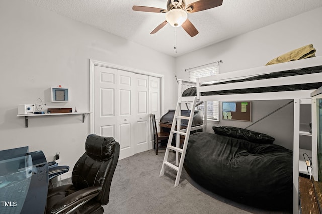 carpeted bedroom featuring a ceiling fan, a closet, and a textured ceiling