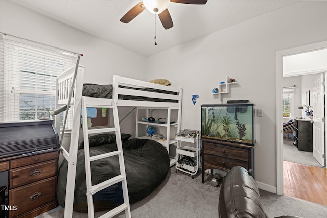 bedroom featuring ceiling fan, baseboards, a textured ceiling, and light colored carpet